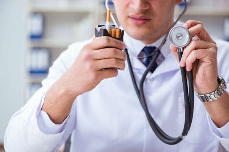 Male doctor in anti-smoking conceptwithcigarette pack