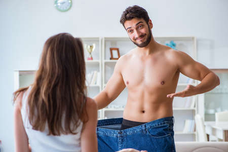 Man in oversized pants in weight loss concept with girlfriend wiの写真素材
