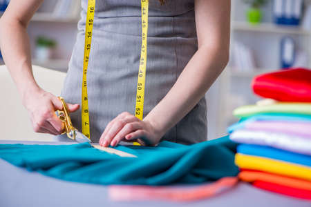 Woman tailor working on a clothing sewing stitching measuring fabric