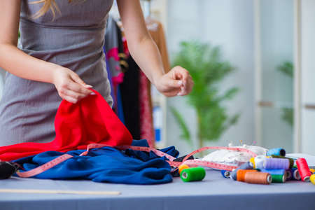 Young woman tailor working in workshop on new dressの写真素材