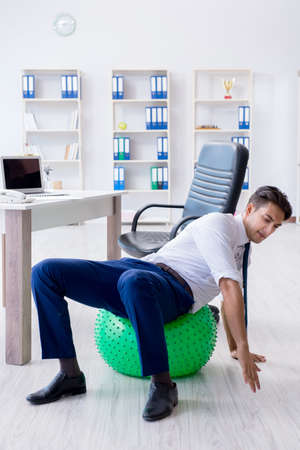 Young businessman doing sports stretching at workplaceの写真素材