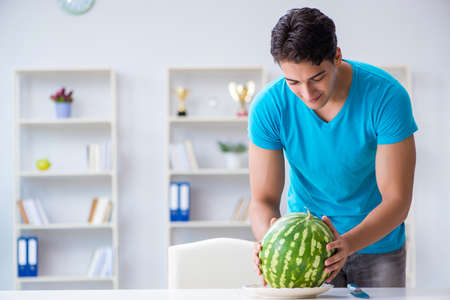 Man eating watermelon at homeの写真素材