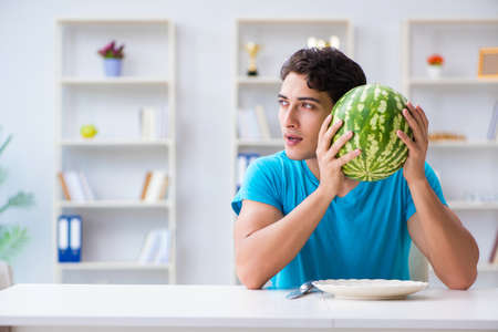Man eating watermelon at homeの写真素材