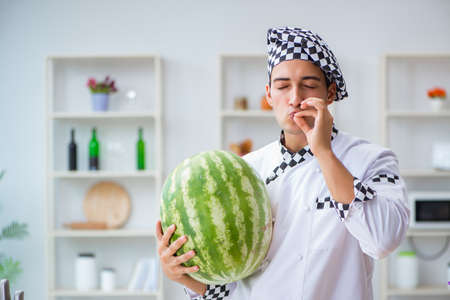 Male cook with watermelon in kitchenの写真素材