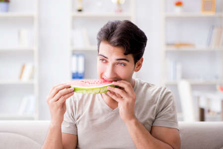Man eating watermelon at homeの写真素材