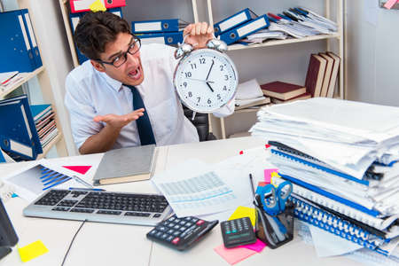 Businessman working in the office with piles of books and papers