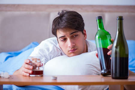 Man alcoholic drinking in bed going through break up depressionの写真素材