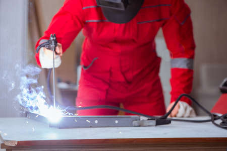 Young repairman with a welding gun electrode and a helmet weldin