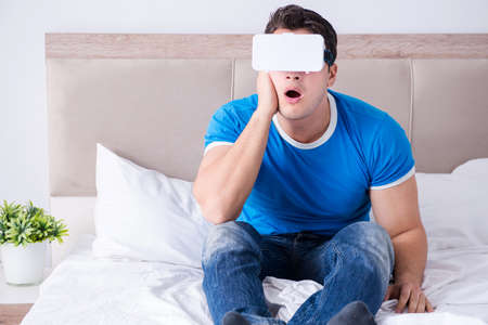 Young man in bed wearing a vr virtual reality head set