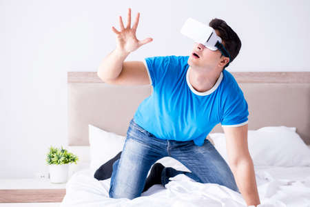 Young man in bed wearing a vr virtual reality head set