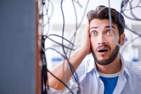 Electrician trying to untangle wires in repair conceptの写真素材