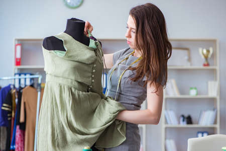 Woman tailor working on a clothing sewing stitching measuring fabricの写真素材