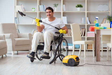 Disabled man with vacuum cleaner at homeの写真素材