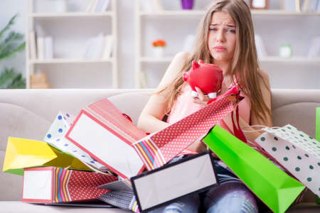 Young woman with shopping bags indoors home on sofaの写真素材