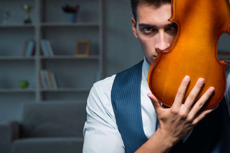 Young musician man practicing playing violin at homeの写真素材