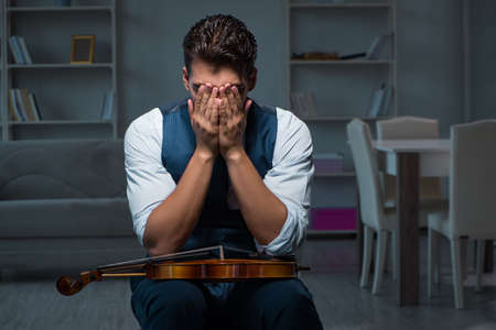 Young musician man practicing playing violin at homeの写真素材