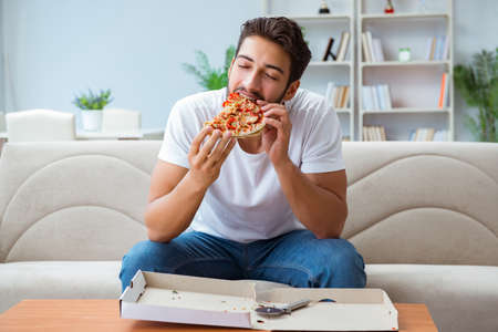 Man eating pizza having a takeaway at home relaxing restingの写真素材