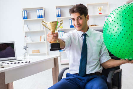 Young businessman doing sports stretching at workplaceの写真素材