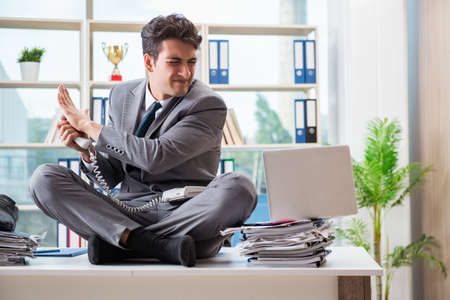 Businessman sitting on top of desk in officeの写真素材