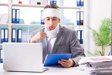 Injured businessman working in the officeの写真素材