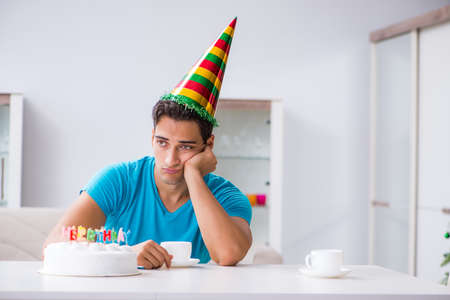 Young man celebrating birthday alone at homeの写真素材