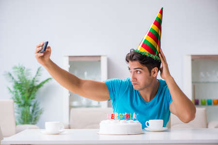 Young man celebrating birthday alone at homeの写真素材