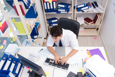 Businessman working in the office with piles of books and papers