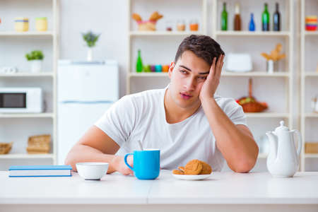 Man falling asleep during his breakfast after overtime workの写真素材
