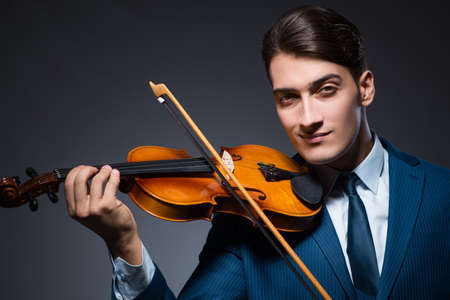Young man playing violin in dark room