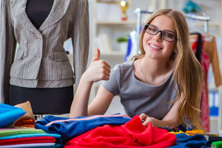 Young woman tailor working in workshop on new dressの写真素材