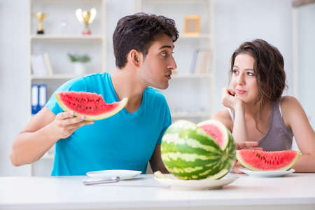 Man and woman eating watermelon at homeの写真素材