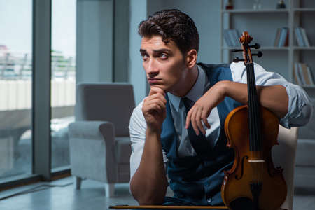 Young musician man practicing playing violin at home