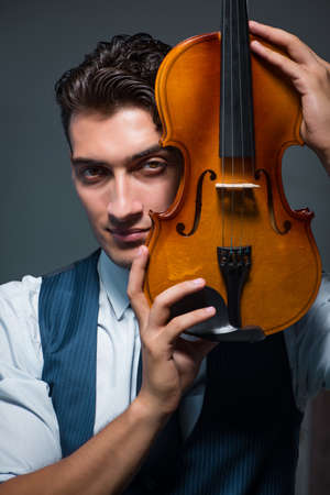 Young musician man practicing playing violin at homeの写真素材