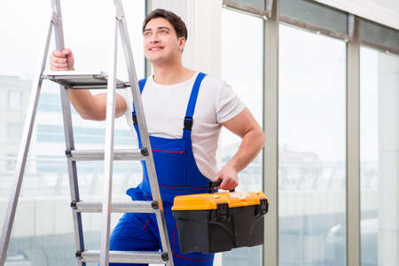 Young repairman climbing ladder at construction  siteの写真素材