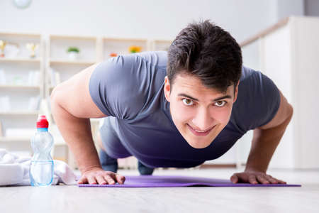 Young man exercising at home in sports and healthy lifestyle conceptの写真素材