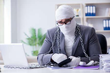 Bandaged businessman worker working in the office doing paperworkの写真素材