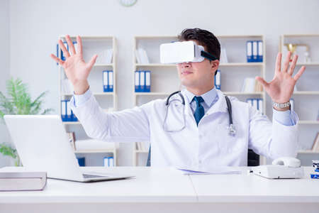 Young doctor with vr virtual reality headset working in the offiの写真素材