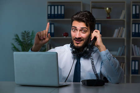 Young man in call center concept working late overtime in office