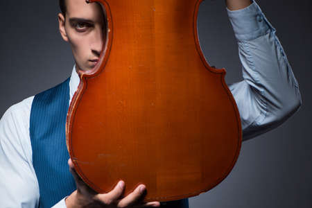 Young man playing cello in dark roomの写真素材