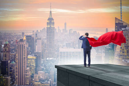 Super hero businessman  on top of building ready for challengeの写真素材
