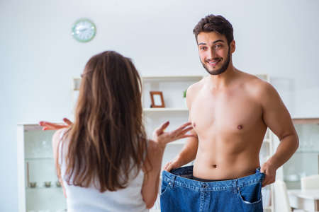Man in oversized pants in weight loss concept with girlfriend wiの写真素材