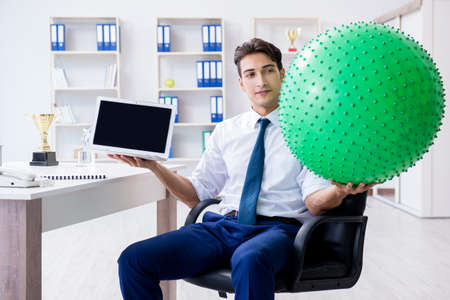 Young businessman doing sports stretching at workplaceの写真素材