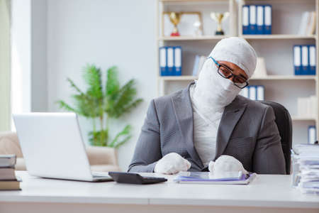Bandaged businessman worker working in the office doing paperworの写真素材