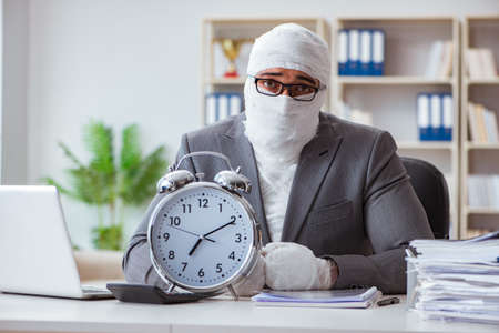 Bandaged businessman worker working in the office doing paperworの写真素材