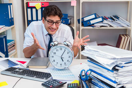 Businessman working in the office with piles of books and papers doing paperwork
