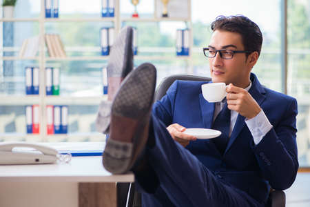 Businessman drinking coffee in the office during breakの写真素材