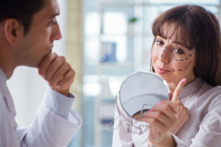 Plastic surgeon preparing for operation on woman faceの写真素材