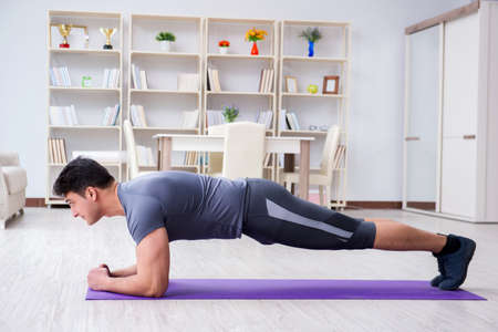 Young man exercising at home in sports and healthy lifestyle con