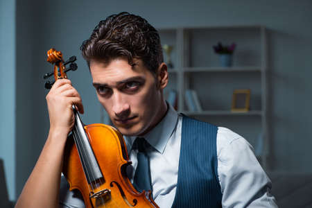 Young musician man practicing playing violin at homeの写真素材