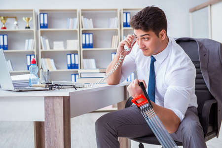Young businessman exercising with elastic expander in officeの写真素材